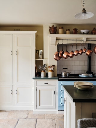 The blue Aga was a remnant from the previous owners. Above hangs Blanches collection of antique copper pans some from...