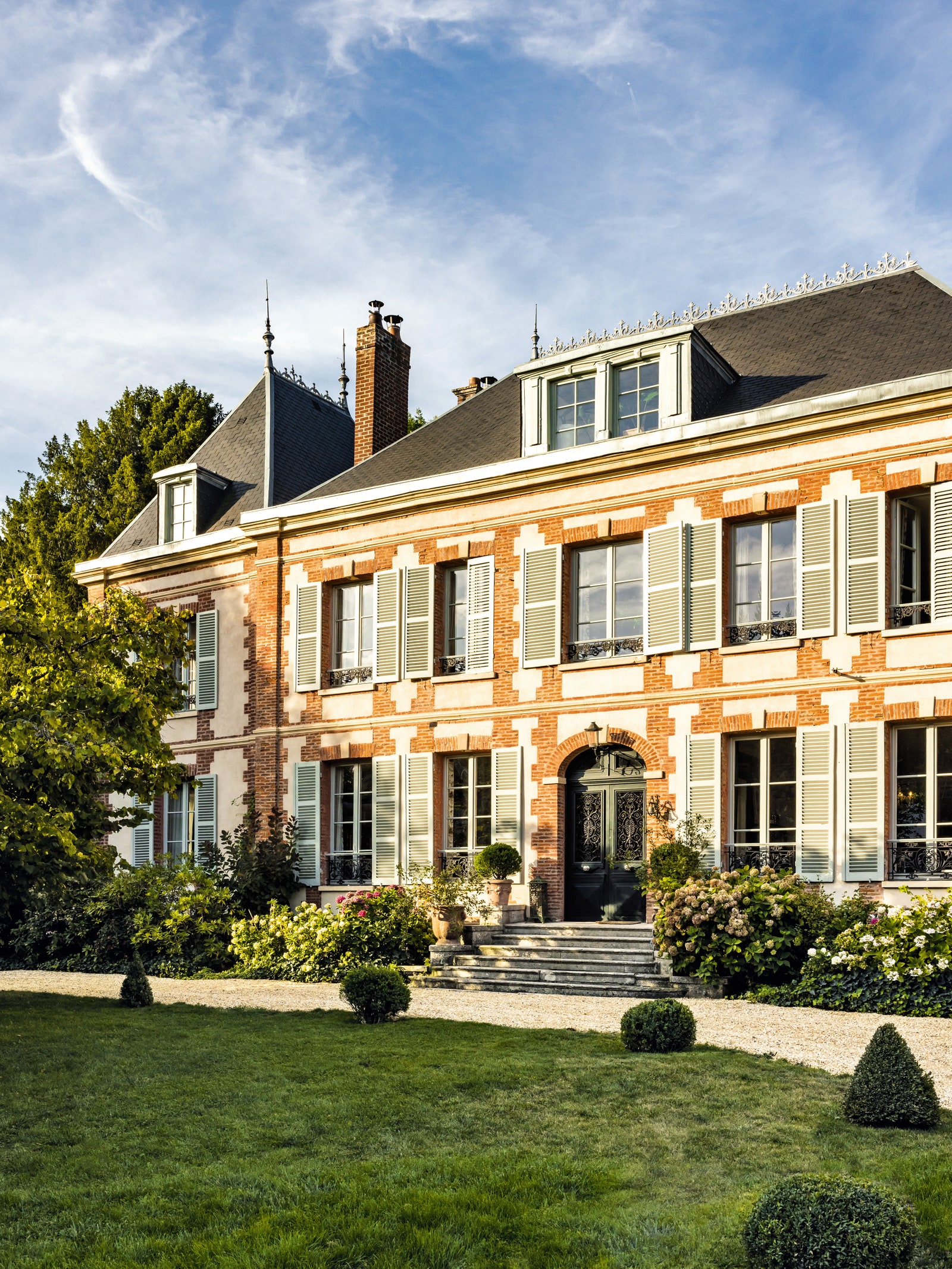 The redbrick and stone façade is set off by the lead roof its metal cresting echoing the shutters.