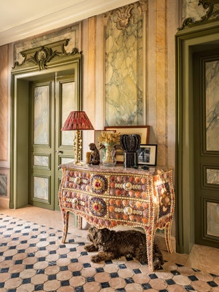 The antique shellwork commode complements the marble floor and trompe loeil wall panels
