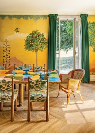 A mural handpainted by Ateliers Gohard provides a vibrant backdrop for a ‘Rainbow dining table from Lauras collection...